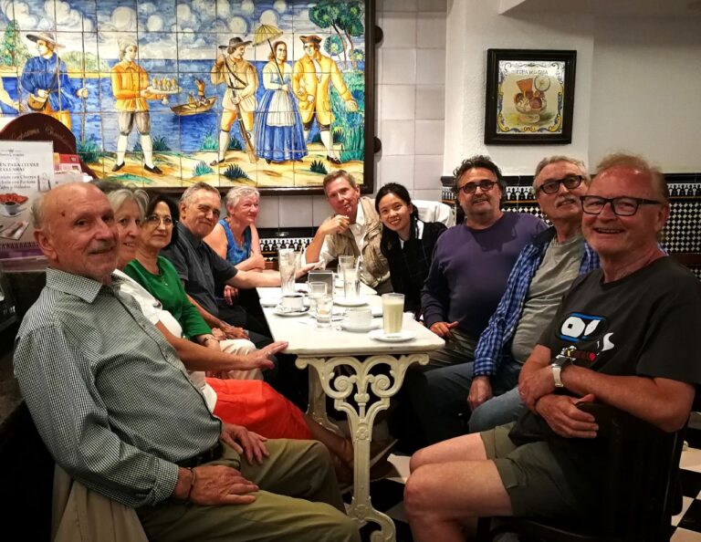 Deu esperantistes al voltant d'una taula de marbre a l'horchateria Santa Catalina de València, amb gots d'orxata; al fons, un plafó de ceràmica valenciana i el terra de quadres blancs i negres.