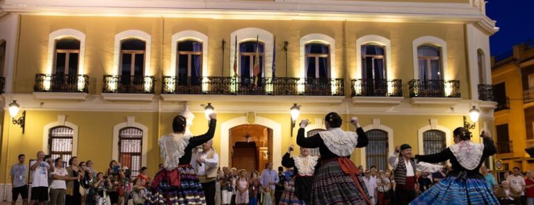 El grup de danses de Xest balla davant de la façana il·luminada de l'Ajuntament per a tancar la recepció. Foto: Ajuntament de Xest.