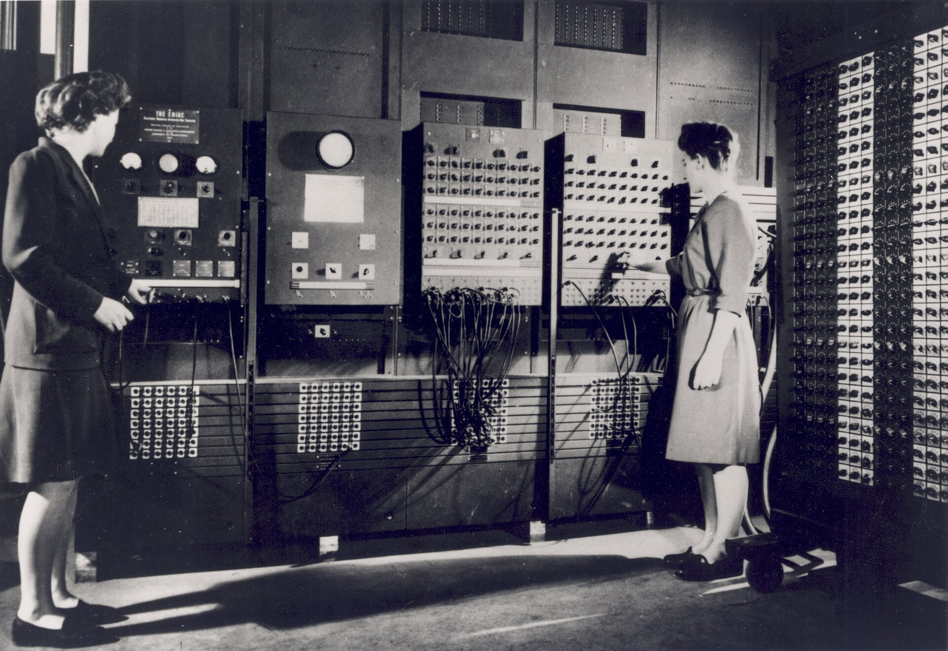 Dues dones treballant davant dels panells de l'ENIAC, plens de cables i botons.